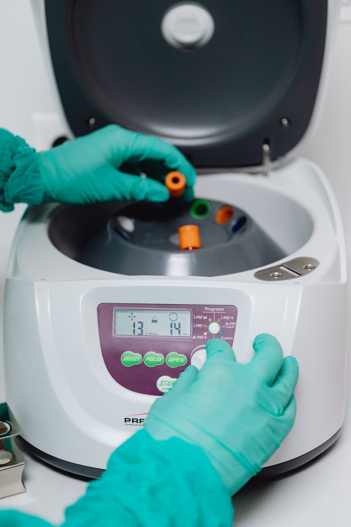 Close-up of a laboratory technician operating a centrifuge machine for sample processing.